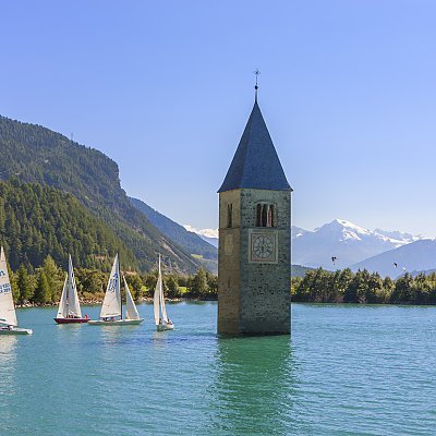 View of sailors and the church tower in the water at lake Lago di Resia